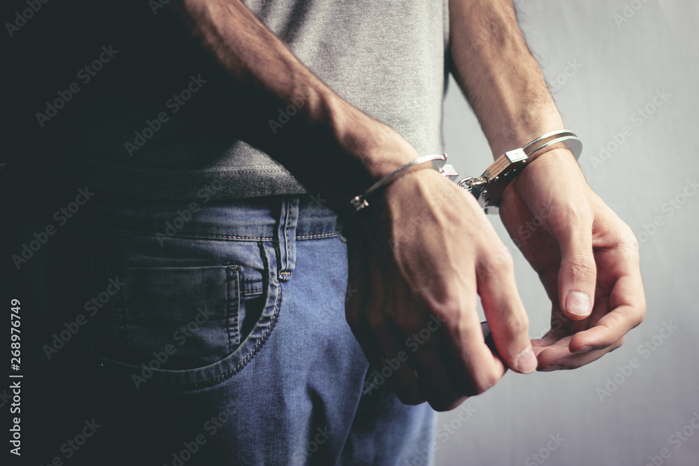 young man hand handcuffs on dark background
