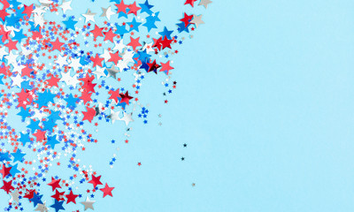 4th of July American Independence Day. Red, blue and white star confetti decorations on blue background. Flat lay, top view, copy space