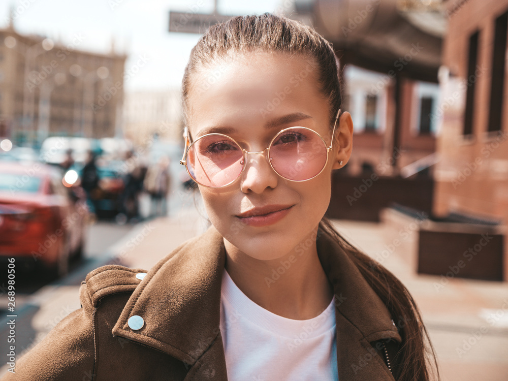 Portrait of beautiful brunette model dressed in summer hipster jacket clothes. Trendy girl posing in the street background. Funny and positive woman in round sunglasses - obrazy, fototapety, plakaty 