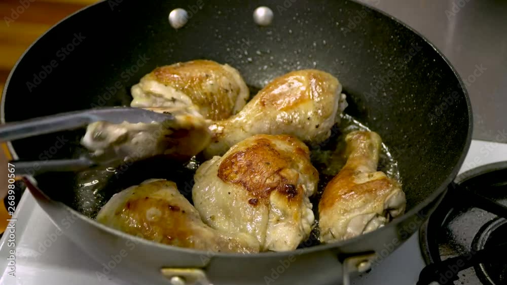 Pan fried chicken drumsticks and thighs in hot oil, use tongs to check browned crispy skin Pan fried chicken drumsticks and thighs in hot oil, use tongs to check browned crispy skin