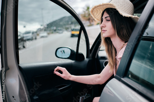 a beautiful woman with a hat opening her car's door