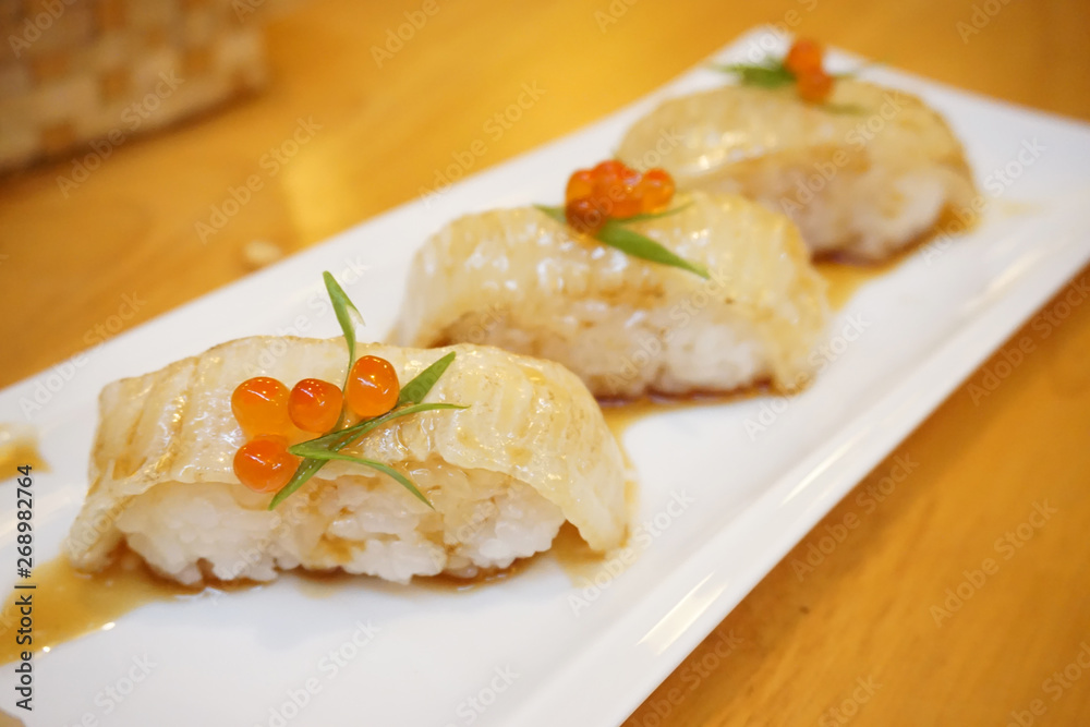 Aburi engawa sushi - Grilled flatfish (Fluke fin) on rice topping with salmon roe (Ikura) served with wasabi and pickled ginger, Japanese traditional food.
