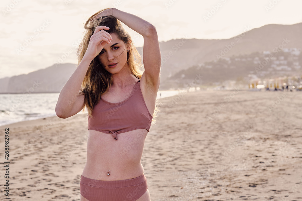 a young model in bikini at sunset looking at the camera a young model in bikini at sunset looking at the camera