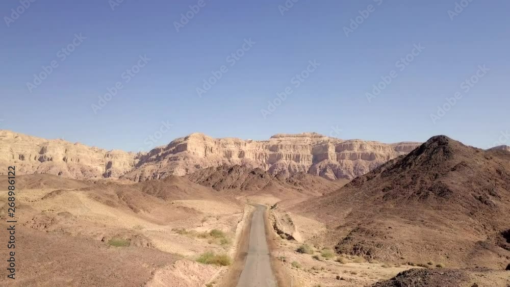 Long stretch of an old Desert road with mountains and blue sky in the background, Aerial footage. Long stretch of an old Desert road with mountains and blue sky in the background, Aerial footage.