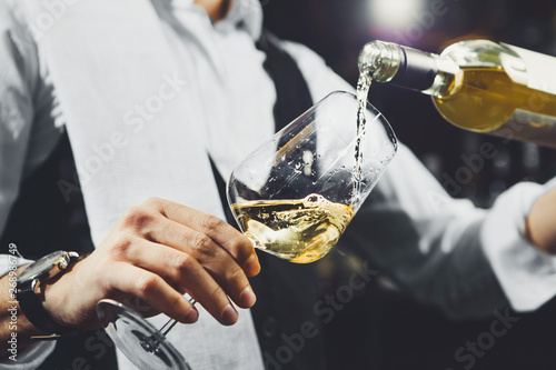 Fotografía Male sommelier pouring white wine into wineglasses.