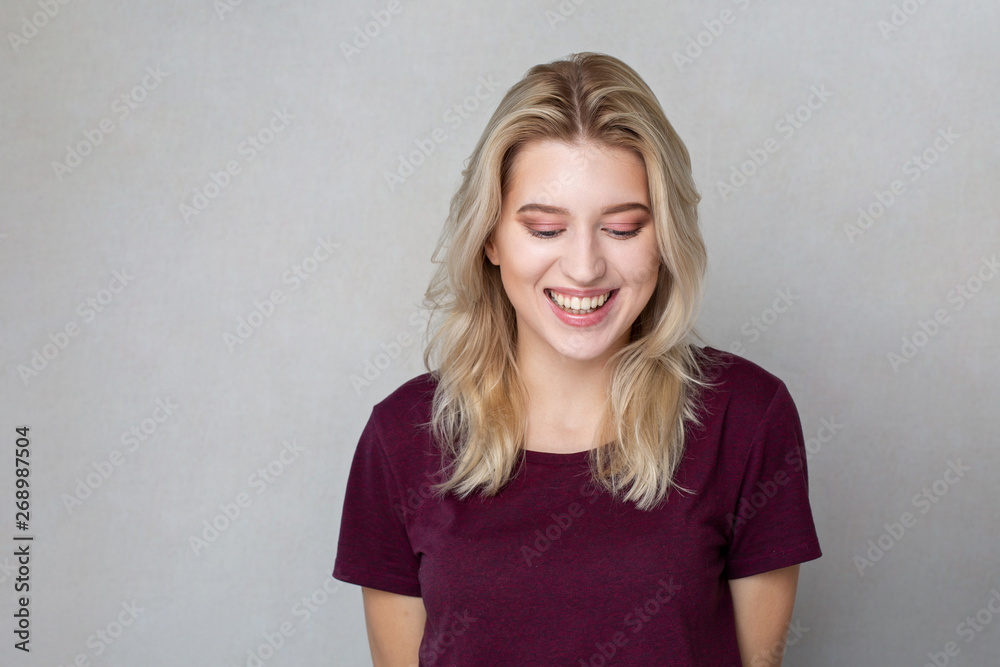 Merry blonde woman with short hair and natural makeup standing over grey wall. Space for text Merry blonde woman with short hair and natural makeup standing over grey wall. Space for text