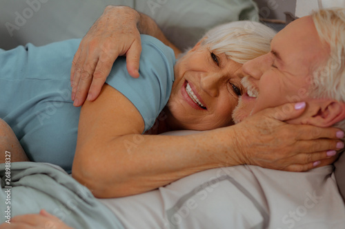 Close-up shot of spouses hugging and lying in the bed