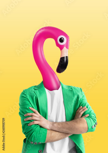 Male body in green jacket headed by a pink swim flamingo against yellow backg...