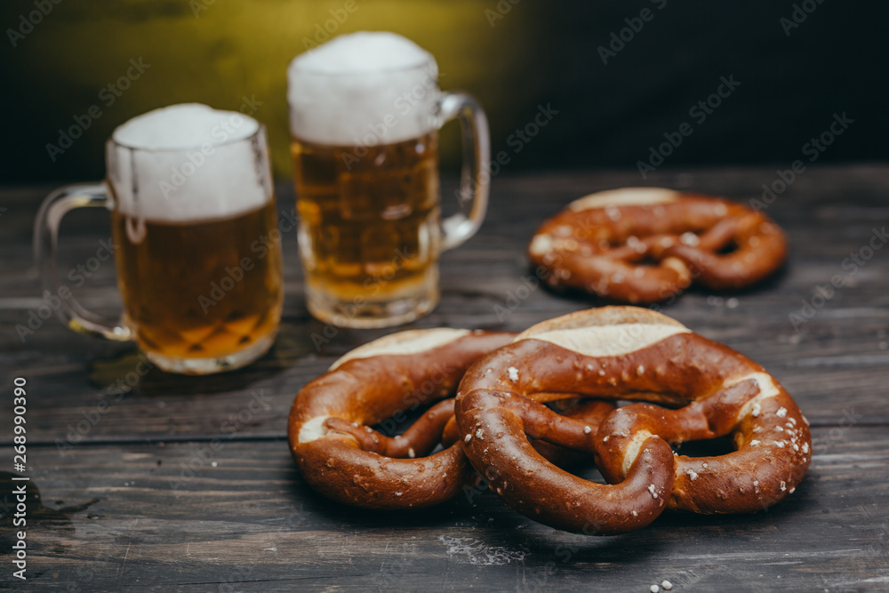 pretzels and beer in mug on dark wooden table pretzels and beer in mug on dark wooden table