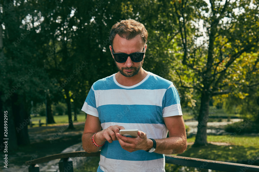 Fototapeta premium Trendy man using cellphone outdoors.