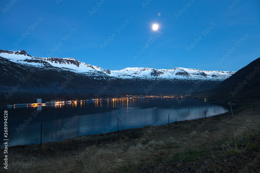 Obraz premium Night view to the small town and snowy mountains in the fjord of Iceland