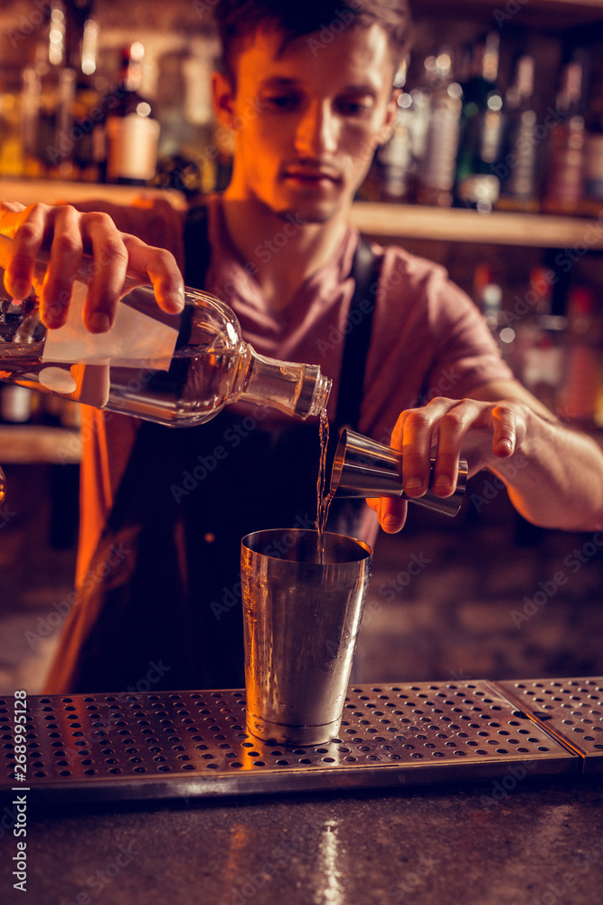 Barman pouring vodka into shaker before making cocktail Barman pouring vodka into shaker before making cocktail
