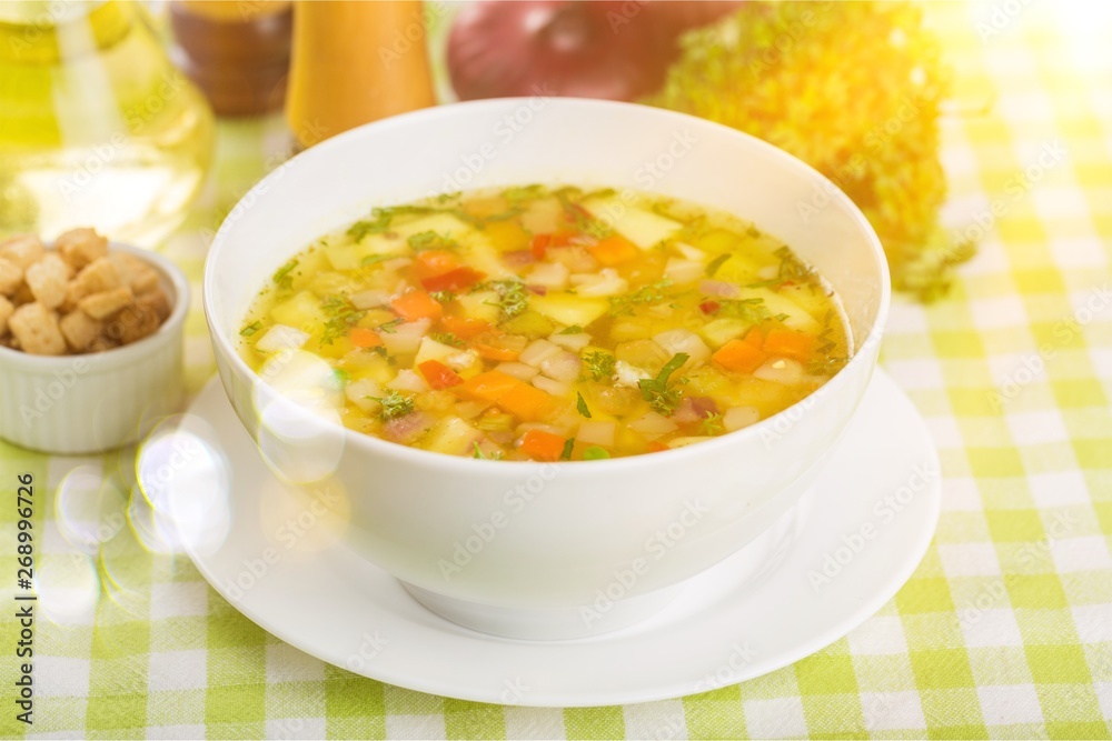 Fresh vegetable soup in plate on tablecloth Fresh vegetable soup in plate on tablecloth