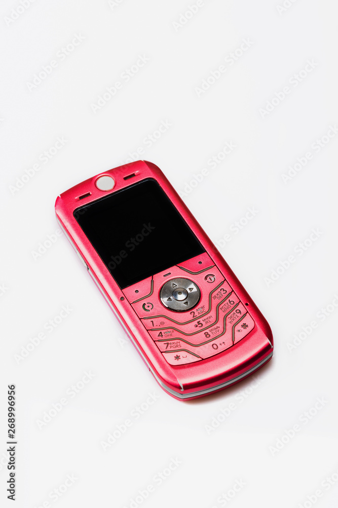 Old, pink mobile phone on white background. Close up. Selective focus. Old, pink mobile phone on white background. Close up. Selective focus.