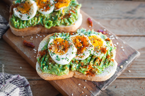 Close-up of avocado and egg toast with herbs and seasonings, on cutting board