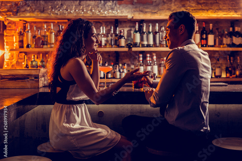 Young lovely couple sitting at the bar stand and talking photo