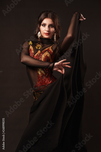 Beautiful belly dancer perfoming exotic dance in red flutter dress photo