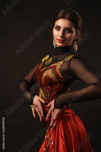 Beautiful belly dancer perfoming exotic dance in red flutter dress