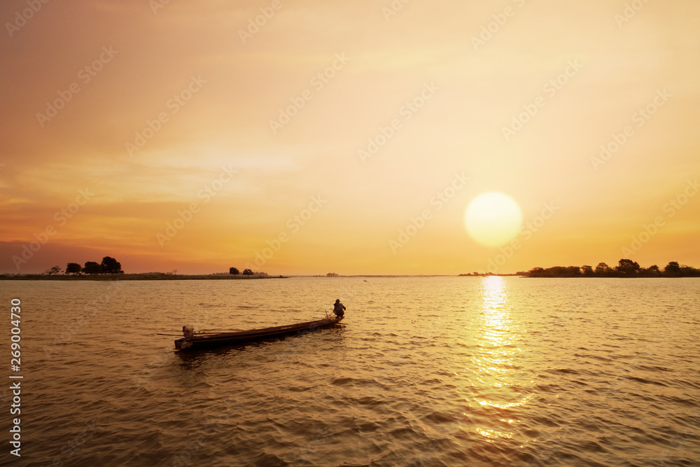 Fisherman on the boat with sunset or sunrise background