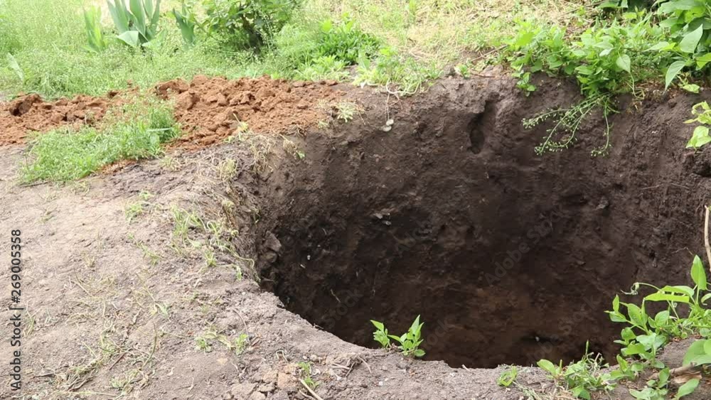Man digging a deep hole with a shovel.
