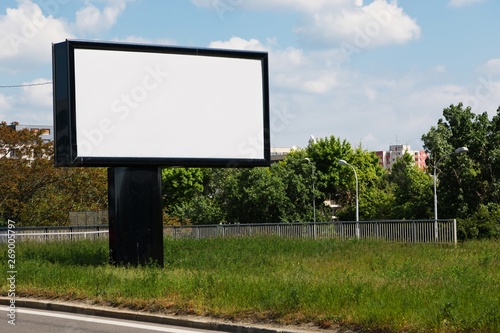 Blank billboard on grass, blue sky background - for new advertisement