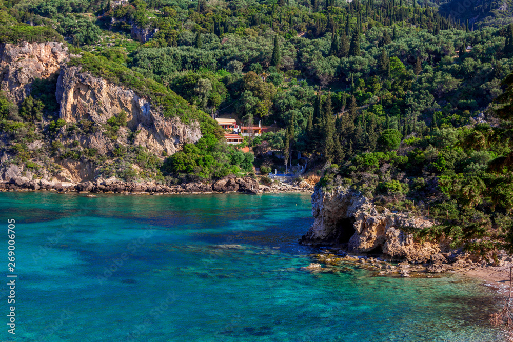 Beautiful landscape with sea, mountains and cliffs, green trees and bushes, rocks in a blue water. Corfu Island, Greece. 