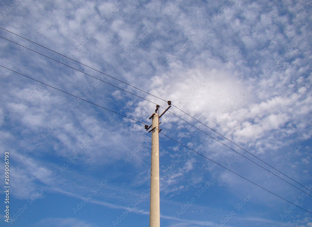 Electric concrete pole with wires. Background sky with light clouds. Metal constructions. Ceramic insulators. Electric concrete pole with wires. Background sky with light clouds. Metal constructions. Ceramic insulators.