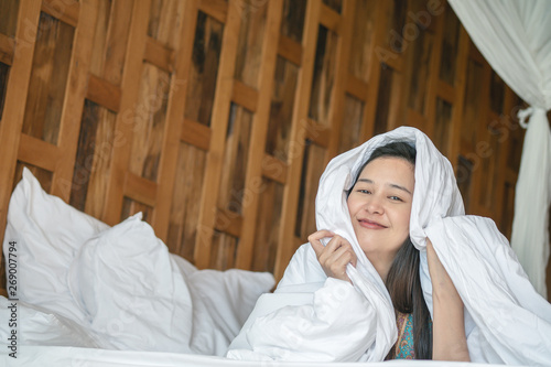 Closeup asian woman lie on bed under blanket with smile face in the morning