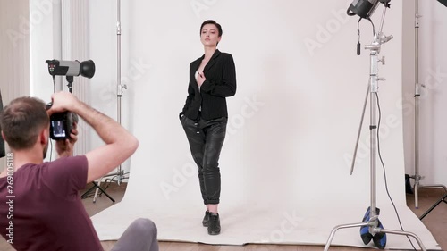 Photographer taking pictures of a professional model in studio over a white background