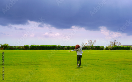 Young business woman standing backwards in a beautiful field landscape outdoors with raise hands arms to the sky