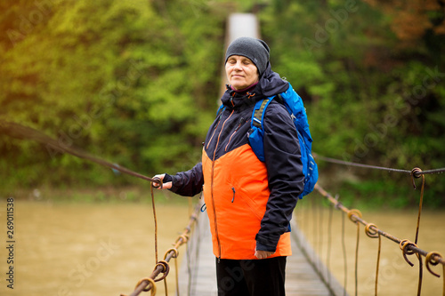 Portrait Of Senior Woman with backpack On Hike cross river in forest