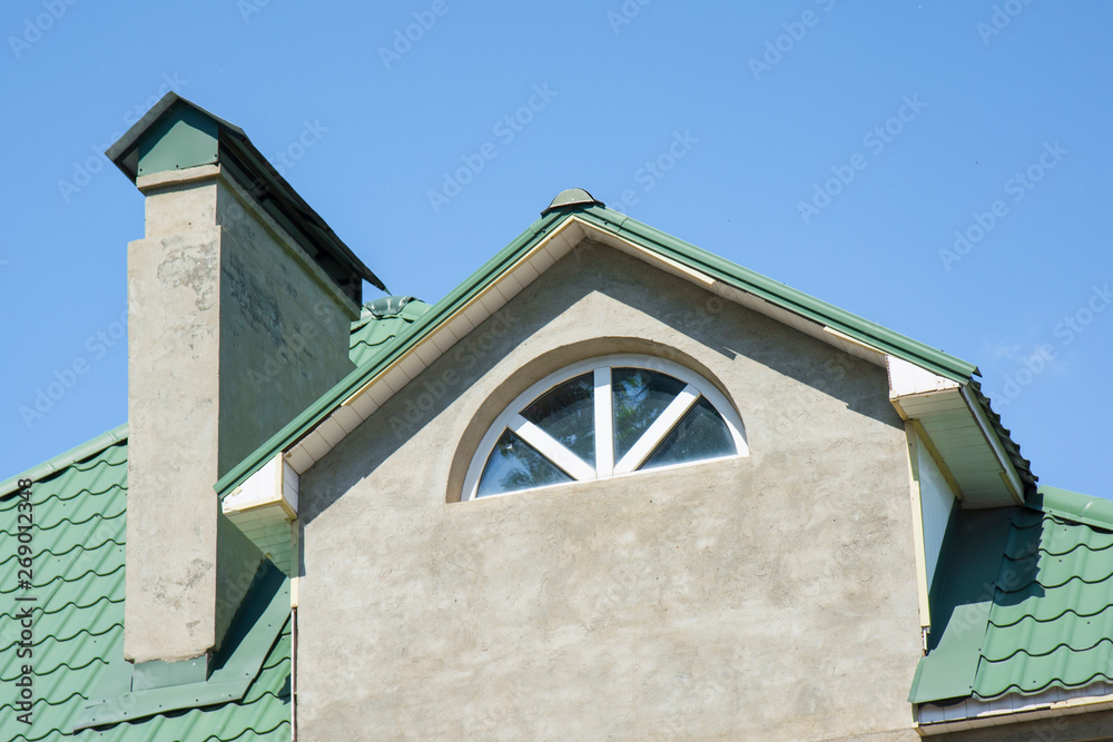 Obraz premium Close-up of building, attic rooms exterior on metal shingle roof, stucco walls and plastic windows.