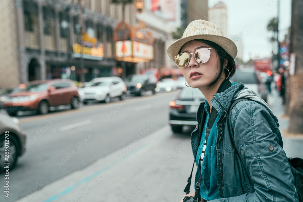 Young beautiful asian woman tourist in sunglasses and hat outdoor in city waiting for cab hailing taxi. travel transport commuter concept. girl standing by road on hollywood boulevard walk of fame. Young beautiful asian woman tourist in sunglasses and hat outdoor in city waiting for cab hailing taxi. travel transport commuter concept. girl standing by road on hollywood boulevard walk of fame.
