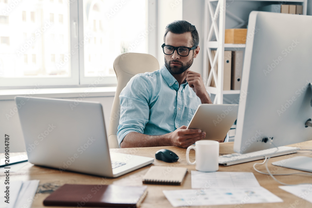 Innovation. Young modern businessman working using digital tablet while sitting in the office