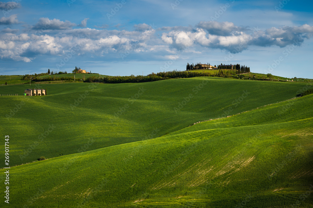 Tuscany spring, rolling hills and windmill on sunset. Rural landscape. Green fields. Italy, Europe Tuscany spring, rolling hills and windmill on sunset. Rural landscape. Green fields. Italy, Europe