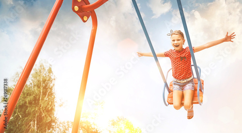 Little laughing girl swing on swing. Happy childchood concept image.