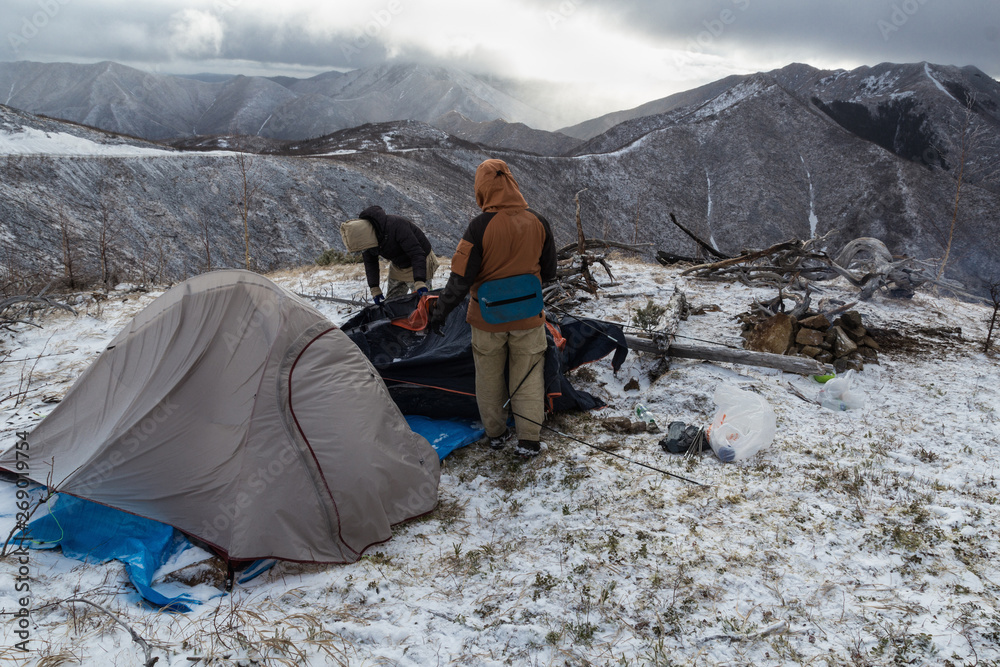 Extreme tourists set up a tent camp in the snow-capped mountains, in a strong wind and blizzard. Extreme tourists set up a tent camp in the snow-capped mountains, in a strong wind and blizzard.