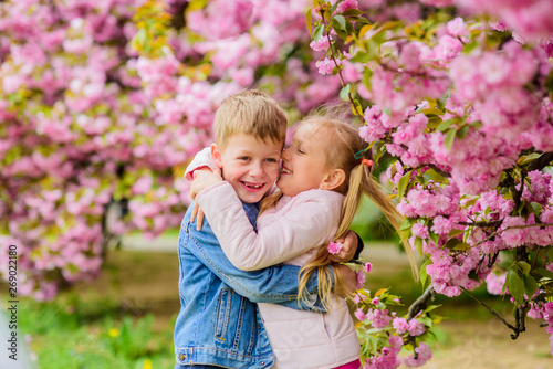 Little girl enjoy spring flowers. Giving all flowers to her. Surprising her. Kids enjoying pink cherry blossom. Romantic babies. Couple kids on flowers of sakura tree background. Tender love feelings