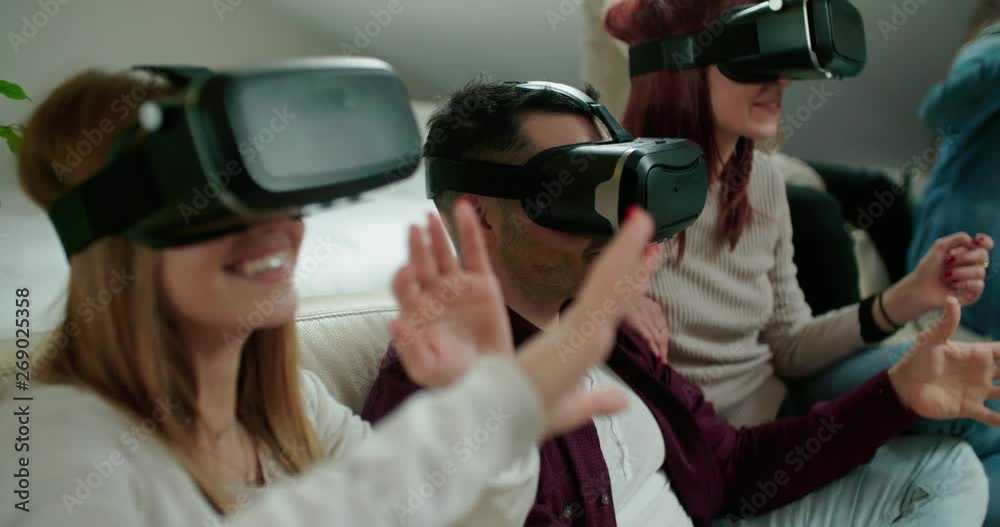 Group of friends using virtual reality simulator glasses in living room. Shot in slow motion Group of friends using virtual reality simulator glasses in living room. Shot in slow motion