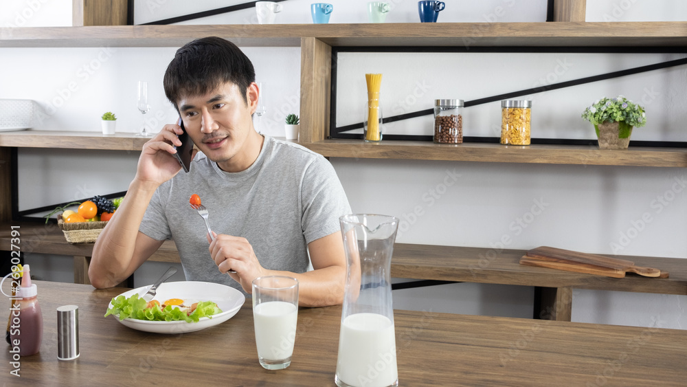 Young handsome Asian eating breakfast and talk about business too, single people lifestyle