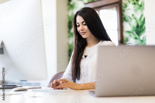 Portrait of beautiful young woman working with laptop in office.