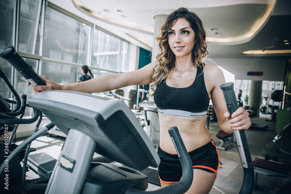 Attractive muscular fitness woman running on nordic ski in gym Attractive muscular fitness woman running on nordic ski in gym