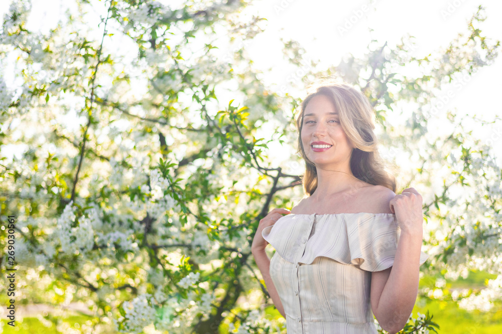 Woman in a blooming orchard at springtime. Enjoying sunny warm day. Retro style dress. Colorful spring moods Woman in a blooming orchard at springtime. Enjoying sunny warm day. Retro style dress. Colorful spring moods