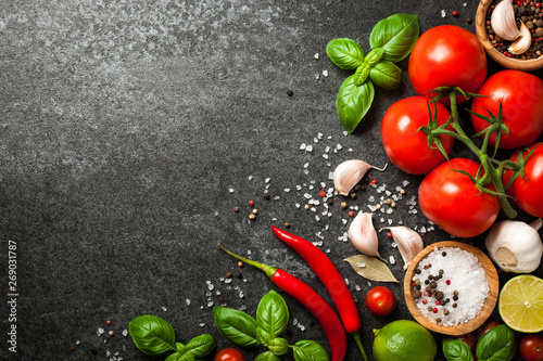 Tomatoes, spices and basil leaves on black background
