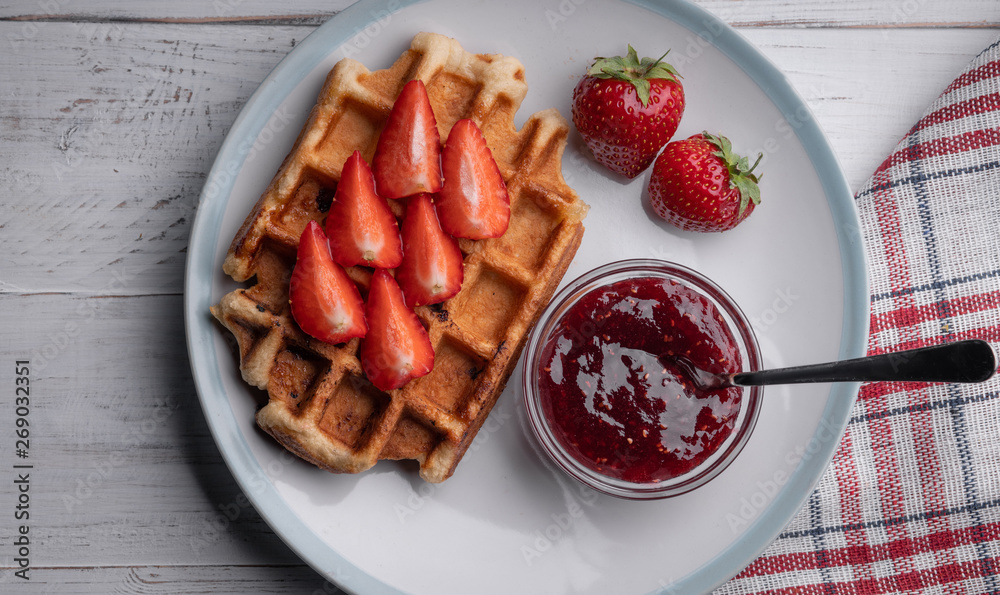 Homemade belgian waffles with strawberry and jam on the white table. Top view. Delicious. Dessert. Sweet food Homemade belgian waffles with strawberry and jam on the white table. Top view. Delicious. Dessert. Sweet food