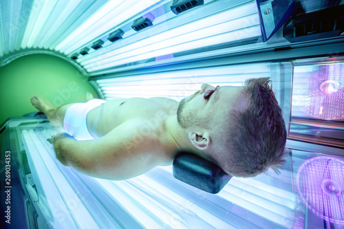 Tablou pe pânză Attractive muscular man in a sunbed