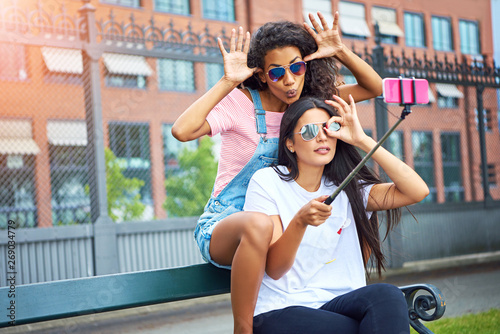 Carefree young friends making faces and taking selfies together outside