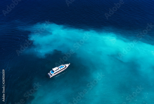 Fast boat at the sea in Bali, Indonesia. Aerial view of luxury floating boat on transparent turquoise water at sunny day. Seascape from air. Top view from drone. Travel - image