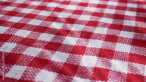 Red white tablecloth, picnic gingham is waving. Pan camera movement close up macro shot checkered fabric cloth background.