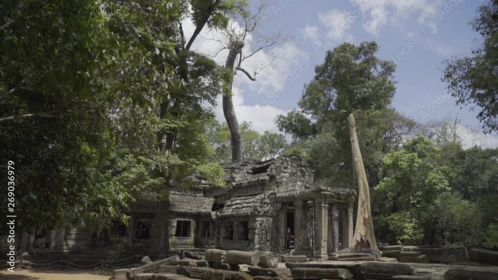 Pull back and reveal an ancient temple in the Angkor Wat temple complex; tourists exploring in the background. Pull back and reveal an ancient temple in the Angkor Wat temple complex; tourists exploring in the background.